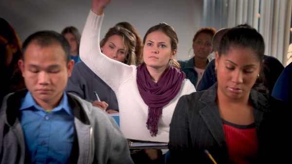 student raising hand in class full of students