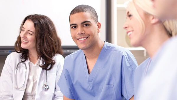 male nurse smiling with two female nurses