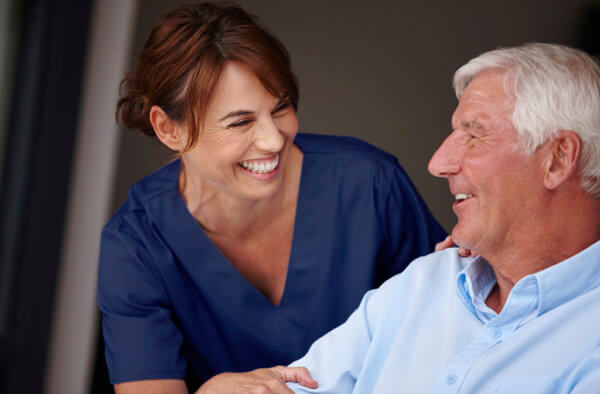 nurse smiling and helping an elderly man