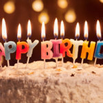 birthday cake with colorful lit happy birthday candles