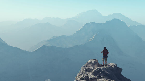 man on top of a mountain overlooking more vast mountains