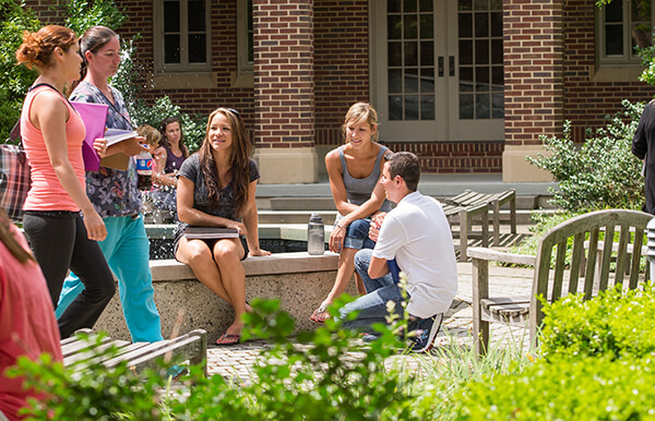 students sitting around courtyard fountain with books