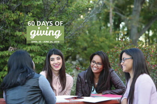Four women sitting around a table outside with books open in front of them