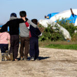 Four children walking away together arm and arm