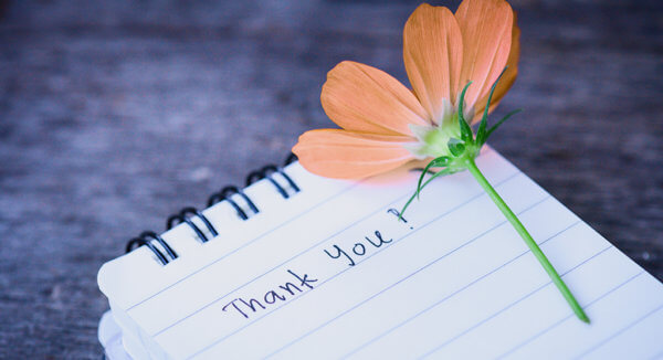 thank you written on a notepad with a flower