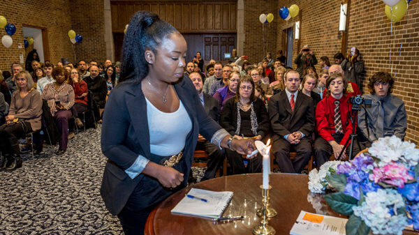 female student light a candle at the Phi Theta Kappa ceremony