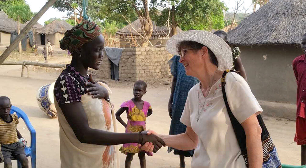 Marilyn Lacey shaking the hand of an African woman