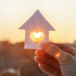 sun coming through a heart shape cut out of the center of a paper house