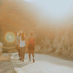 women walking down a road with sun shining on them